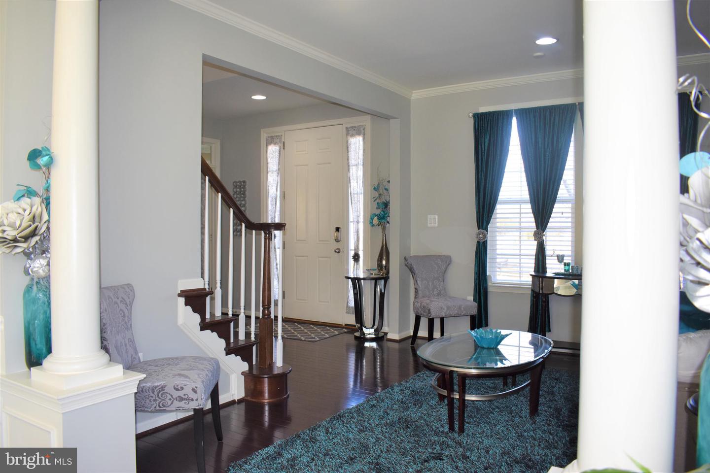 Furnished foyer with a dark wood staircase, hardwood floors, and teal-curtained window.
