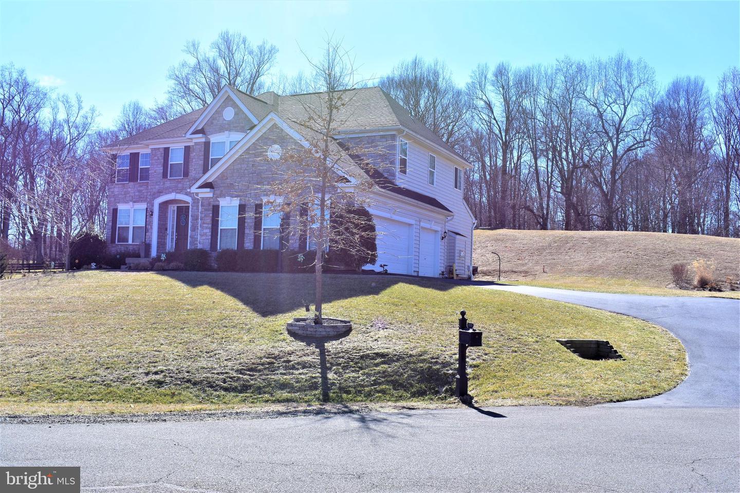 Two-story stone-and-siding house with an attached garage and curved driveway.