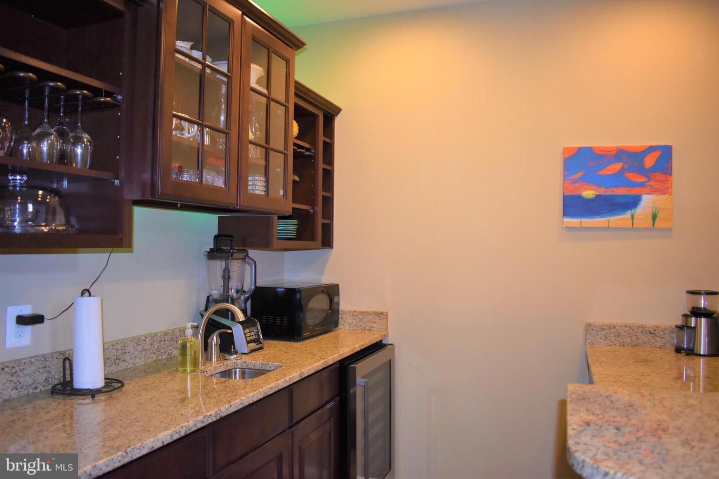 Kitchen with dark wood cabinets, granite counters, a sink, and colorful wall art.