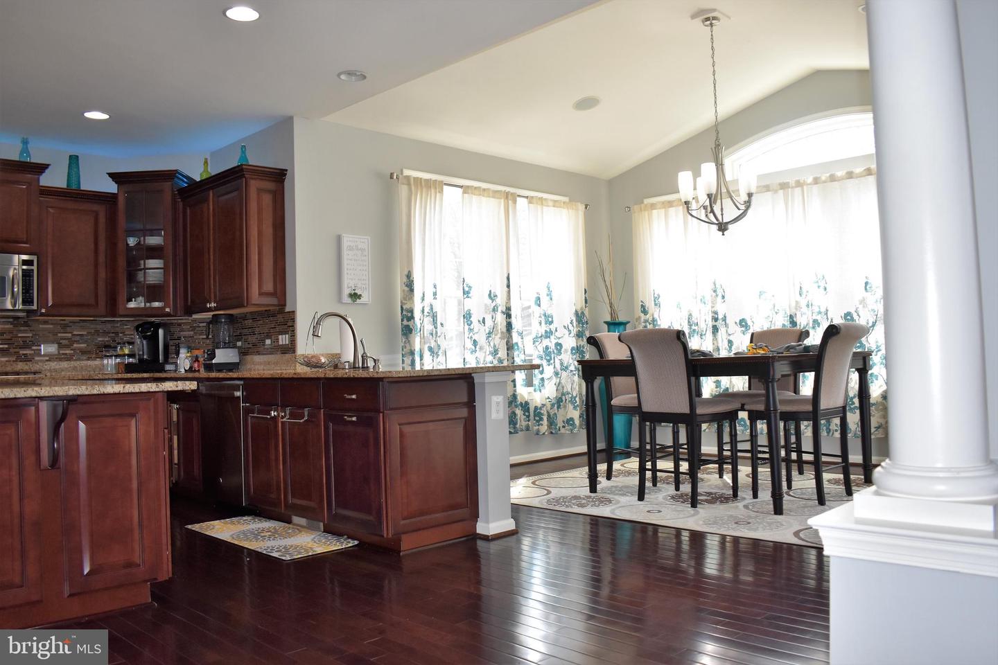 Kitchen and dining area with cherry cabinets, granite counters, and a table beside large windows.