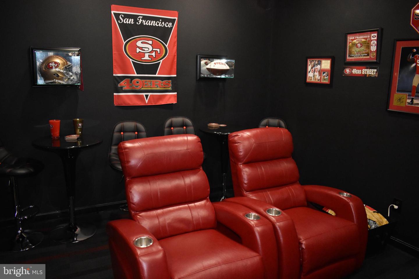 Sports-themed media room with red leather theater recliners and San Francisco 49ers memorabilia.