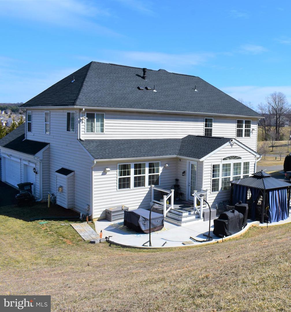 Rear of a two-story house with a large patio, covered seating area, and covered grills.
