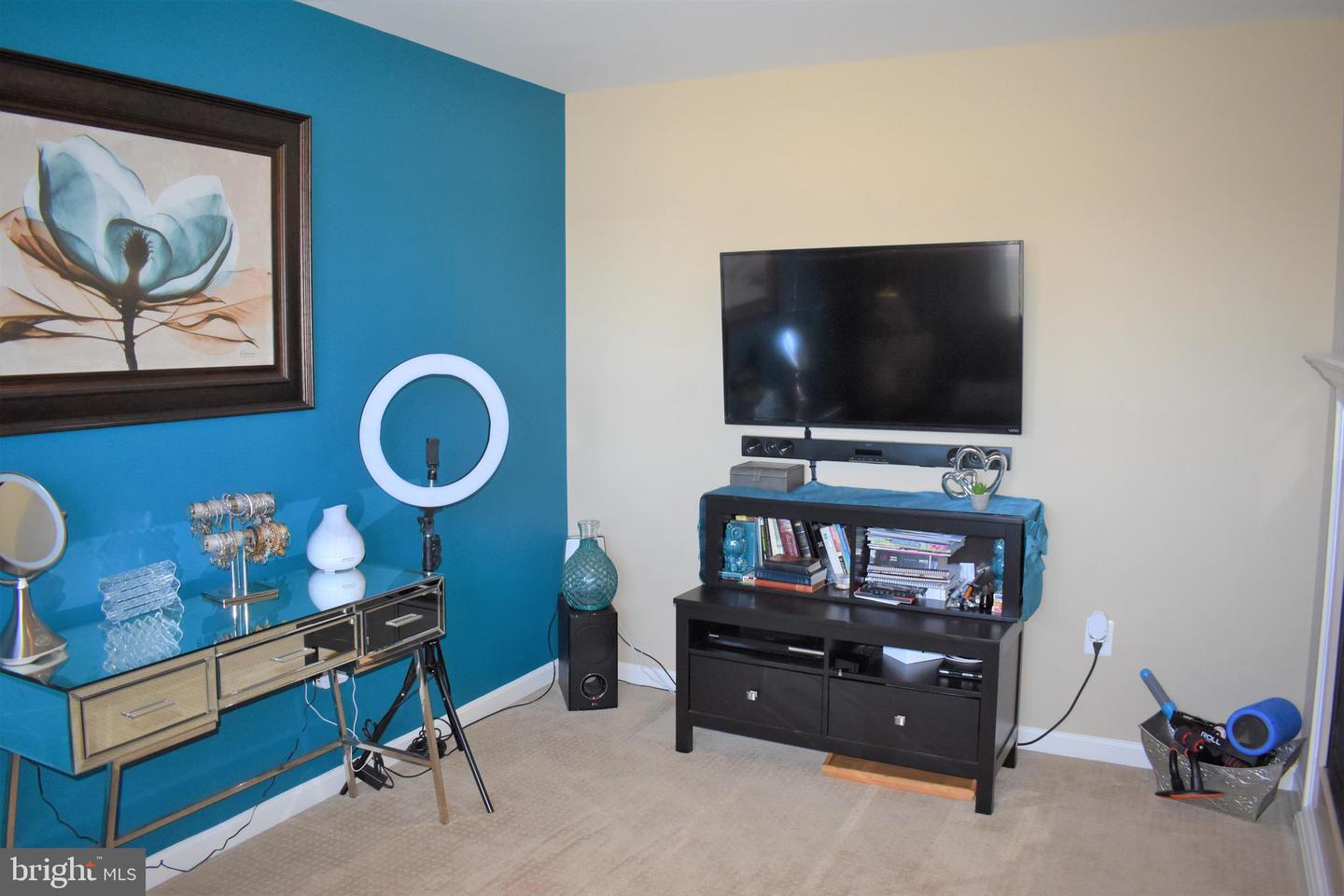 Furnished room with a blue accent wall, mirrored console, and wall-mounted television.