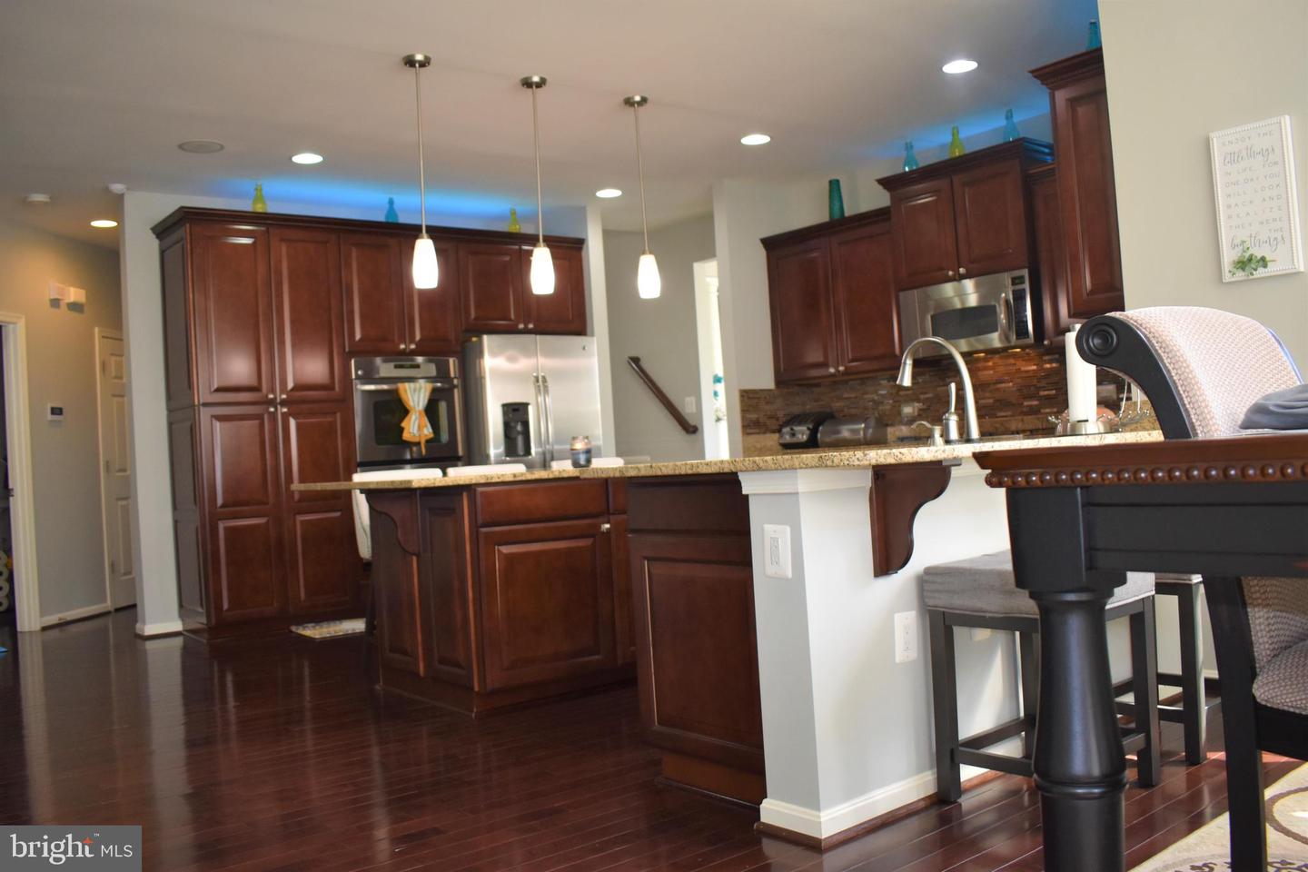 Kitchen with cherry cabinets, stainless steel appliances, and a granite island with raised bar seating.