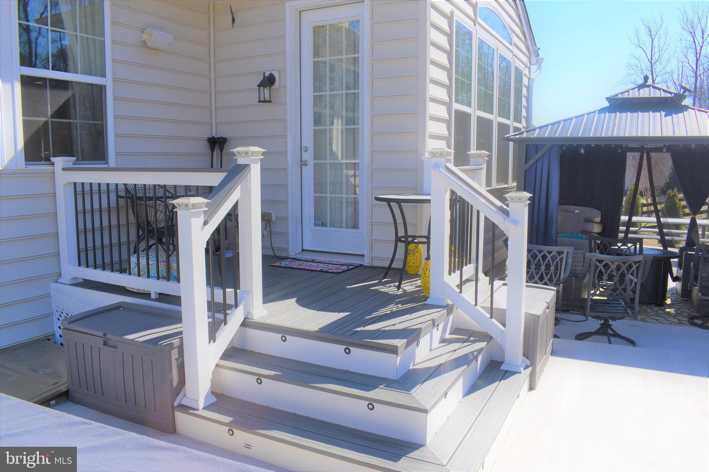 Raised rear deck with white railings, steps, a hot tub, and a covered outdoor seating area.
