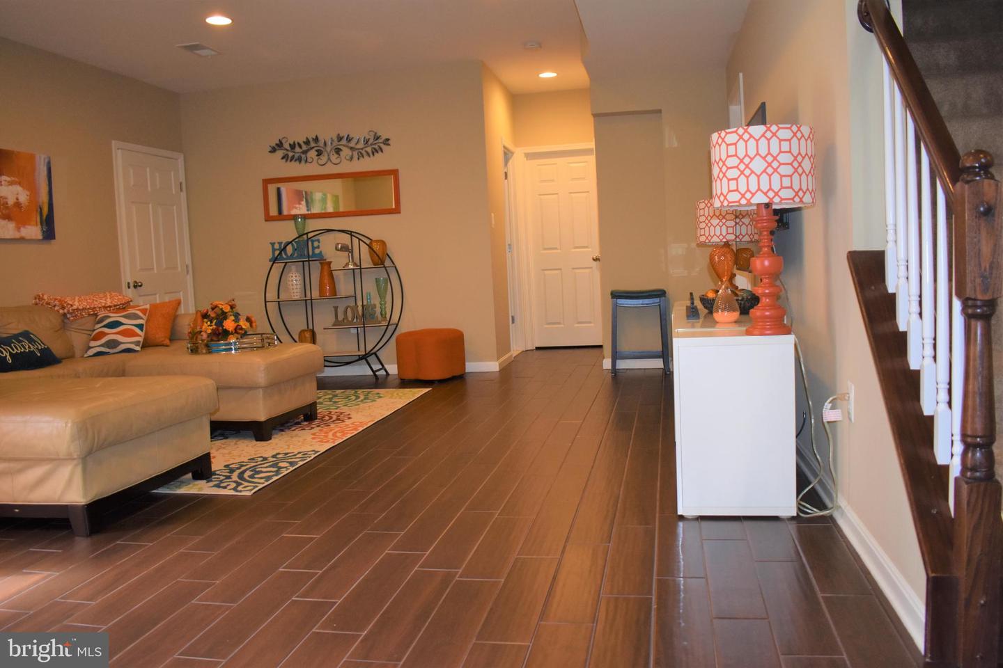 Living room and entry hall with a tan sectional, patterned rug, and dark tile flooring.