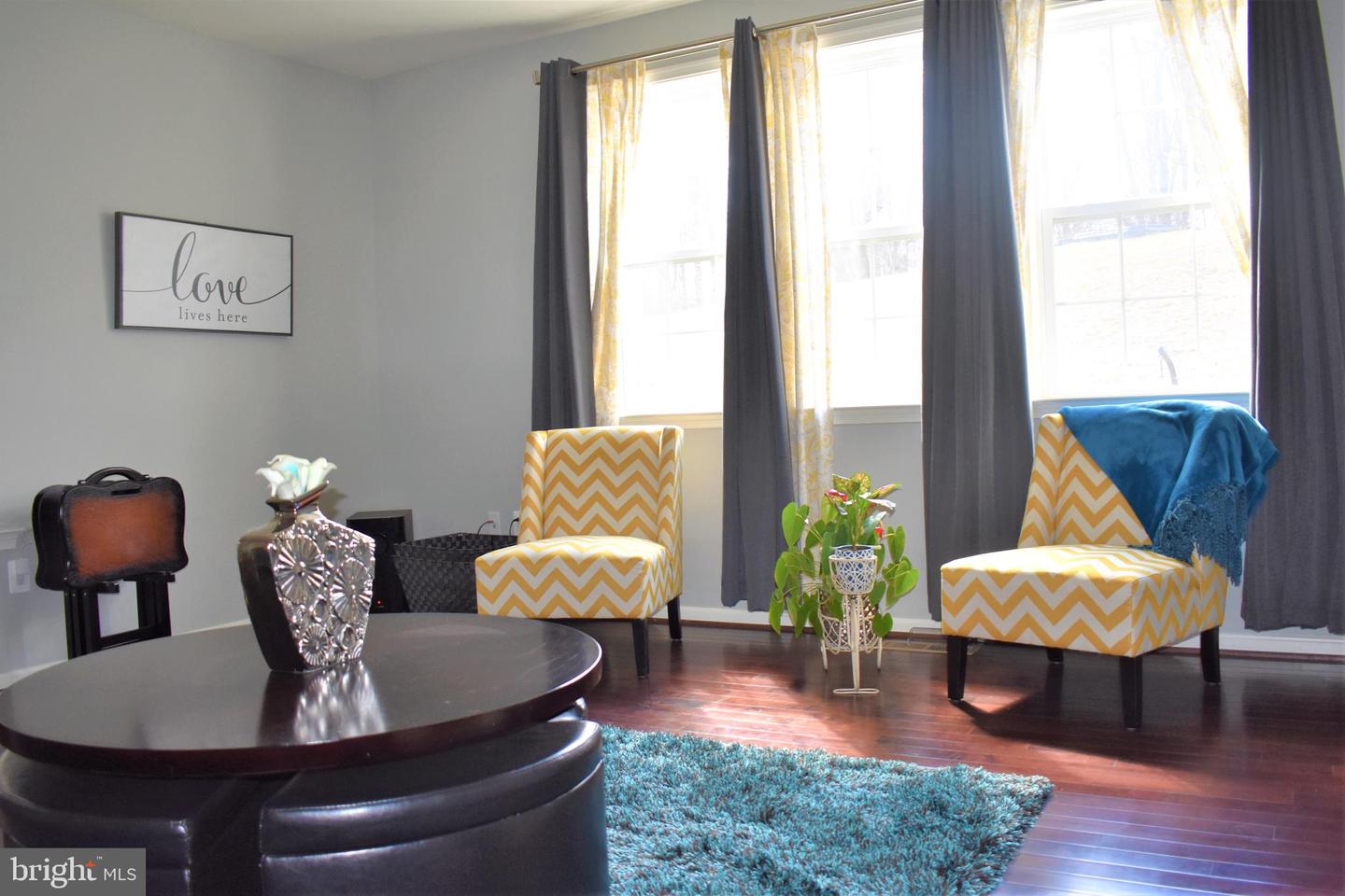 Living room with chevron chairs, tall curtained windows, dark coffee table, and turquoise rug.