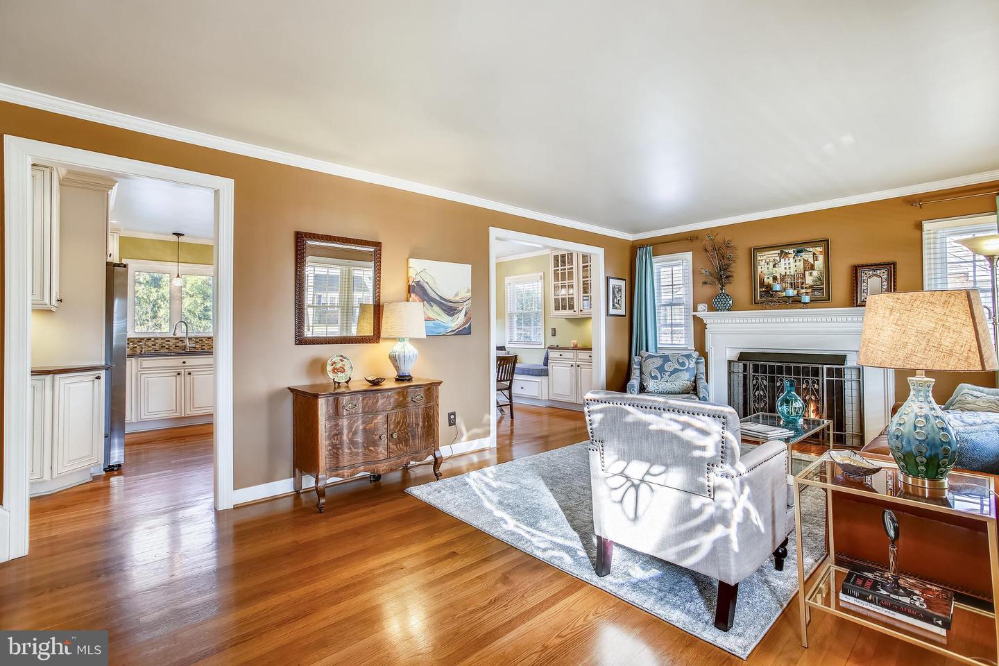 Living room with hardwood floors, tan walls, and a white fireplace.