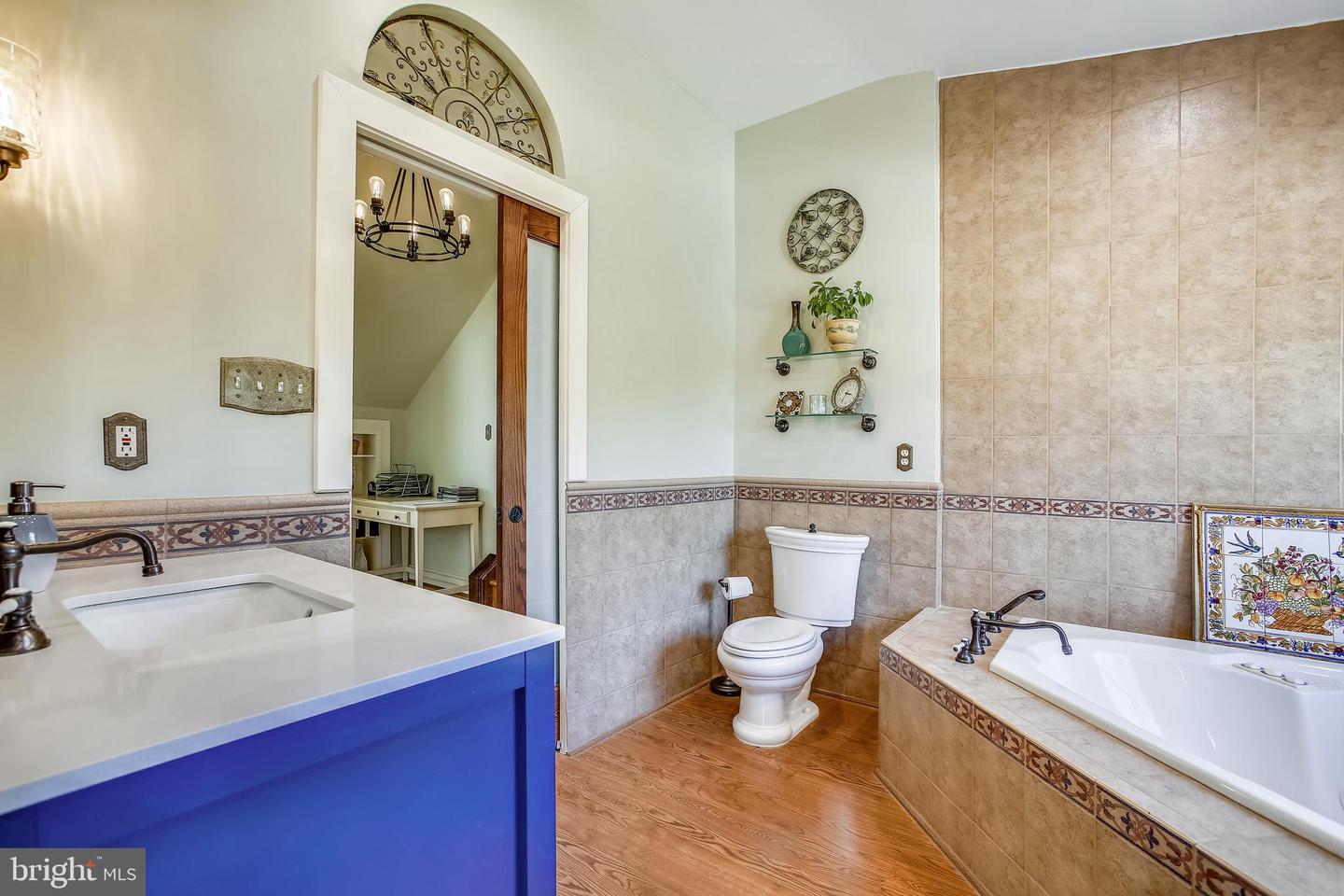 Bathroom with a blue vanity, tan tiled walls, and a bathtub with a decorative tile border.