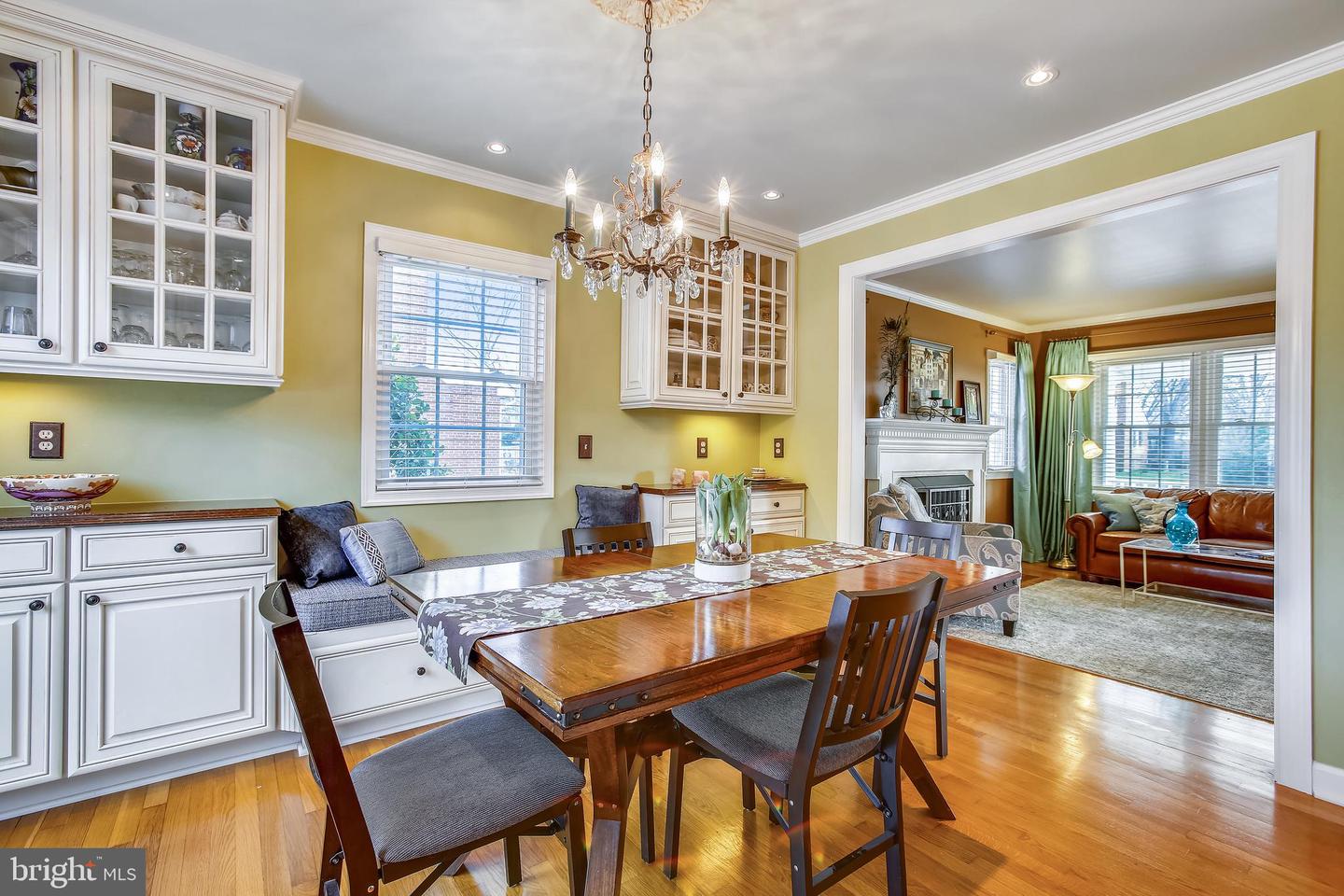 Dining room with a wood table, crystal chandelier, glass-front cabinets, and adjoining living room.