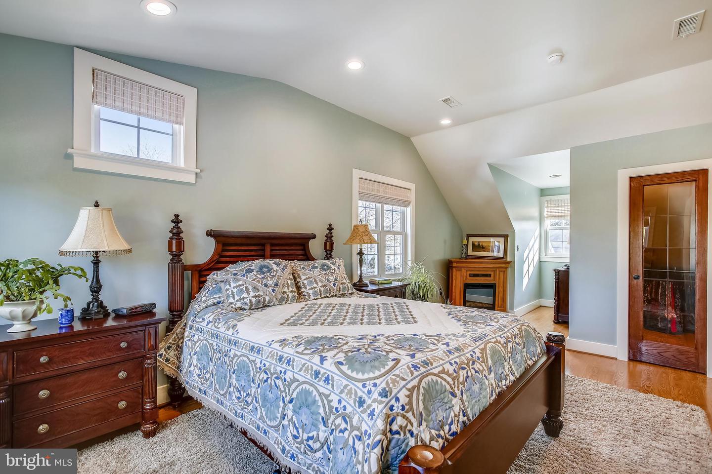 Bedroom with a dark wood four-poster bed, blue-and-white quilt, and pale green walls.