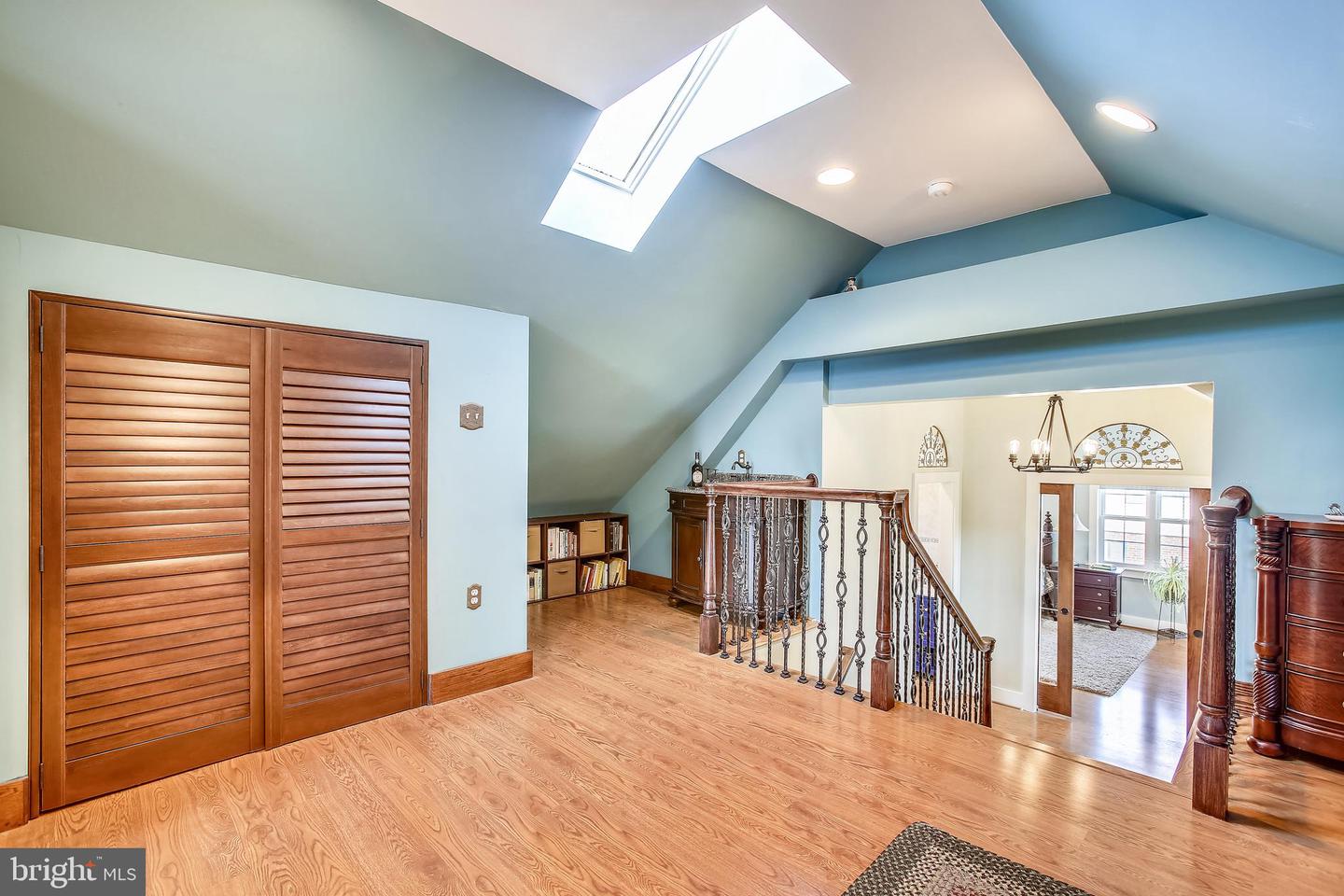 Upper-level loft landing with a skylight, vaulted blue walls, and decorative stair railing.