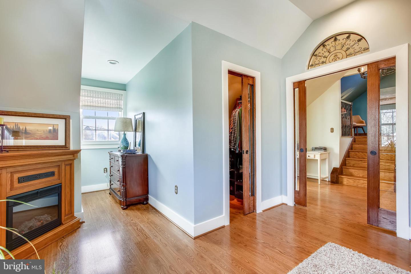 Living room with a fireplace, hardwood floors, and wood-framed glass doors opening toward a staircase.
