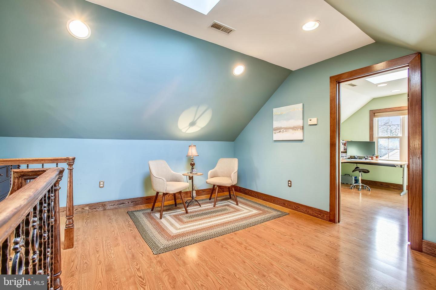 Upstairs loft sitting area with two chairs, a sloped ceiling, and an office doorway.