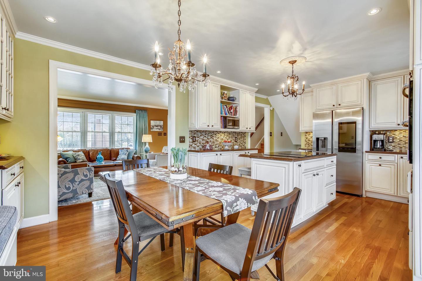 Kitchen and dining area with white cabinetry, stainless steel appliances, a large island, and a wood dining table.