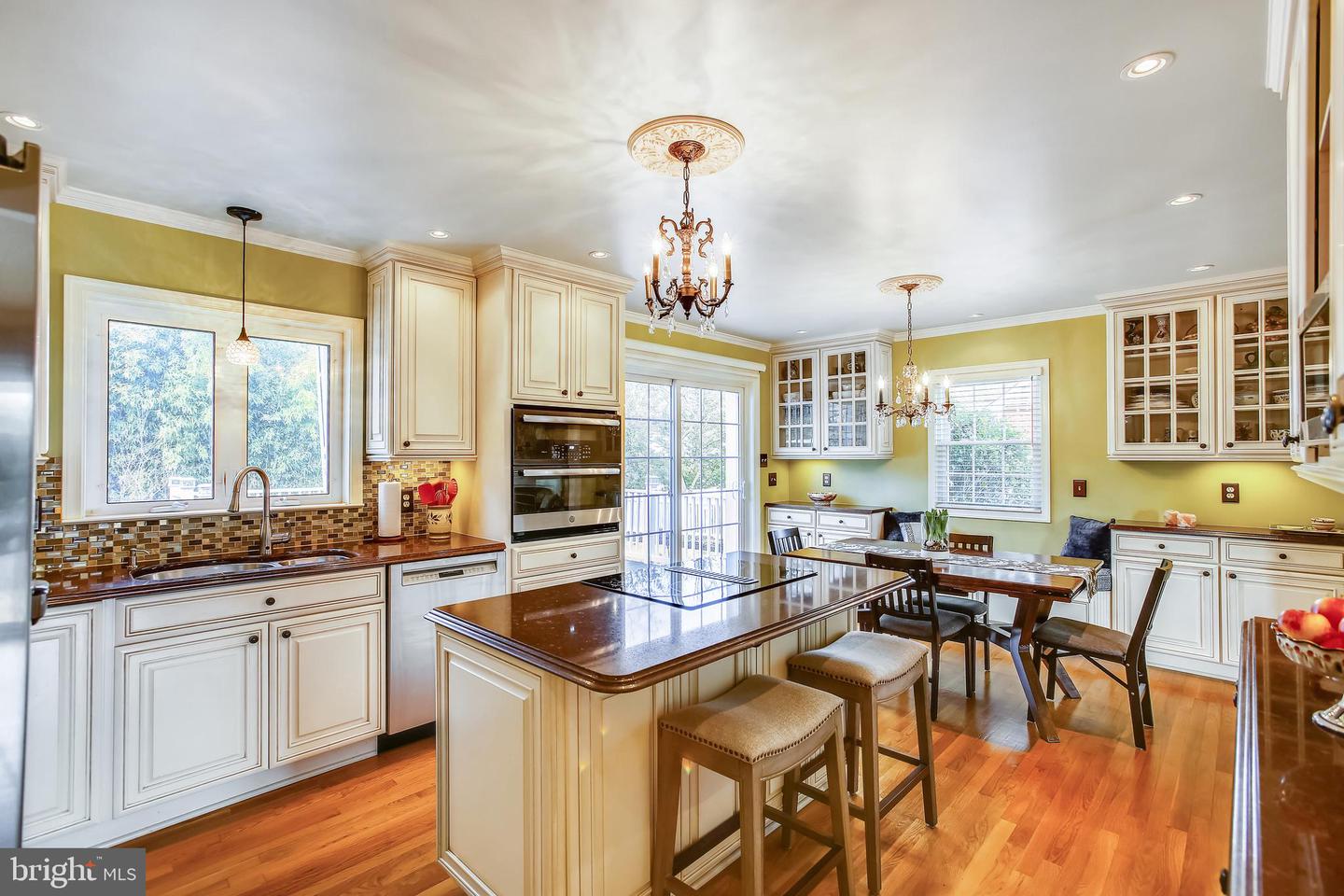 Kitchen with cream cabinetry, a large dark island, double wall ovens, and an adjoining dining area.