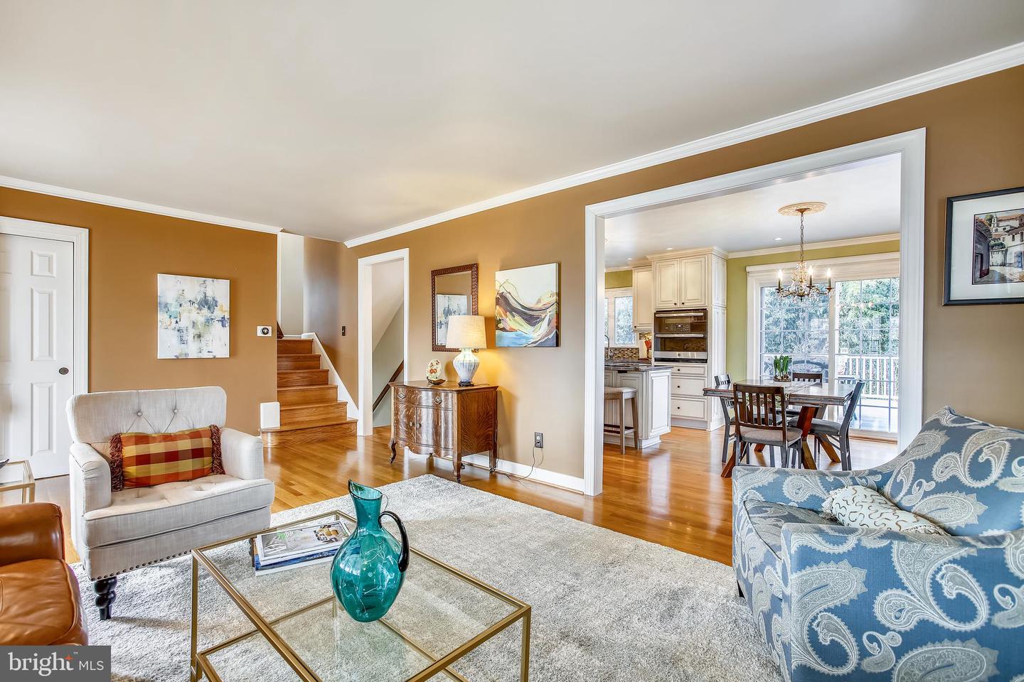 Living room with hardwood floors, tan walls, and an open view into the dining area and kitchen.