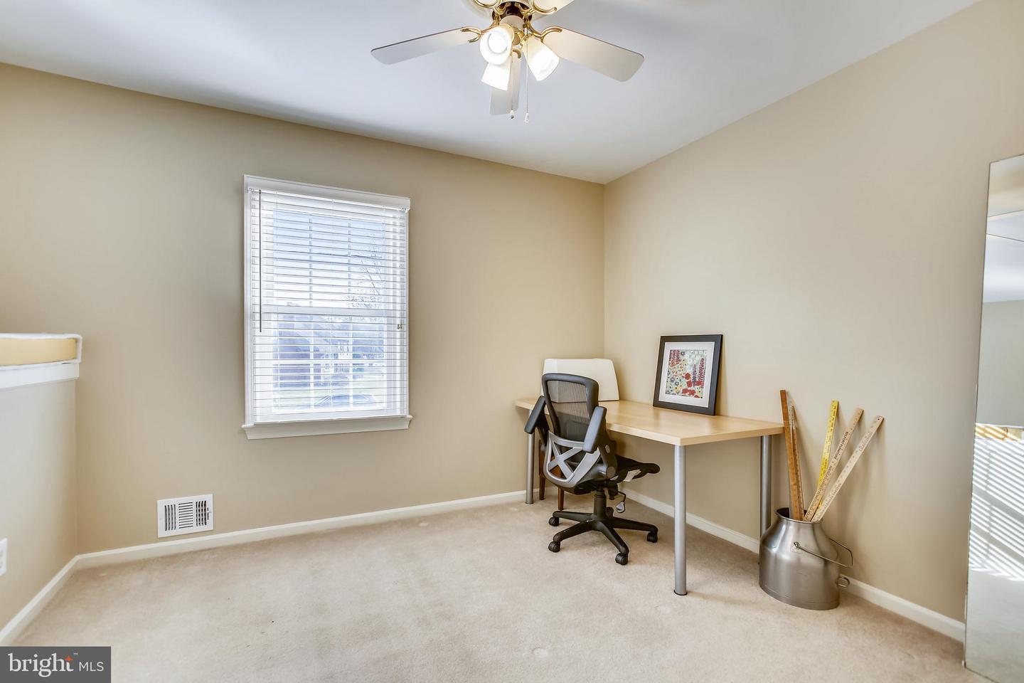 Home office with a desk and swivel chair beside a window with blinds.