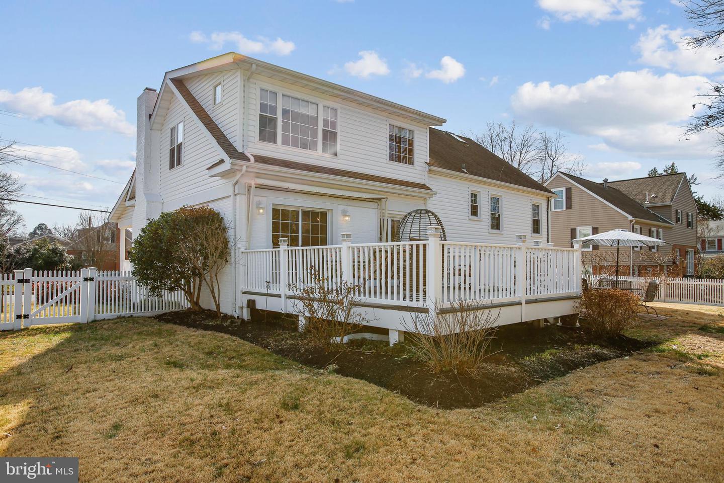 White two-story house with a raised deck and fenced backyard.