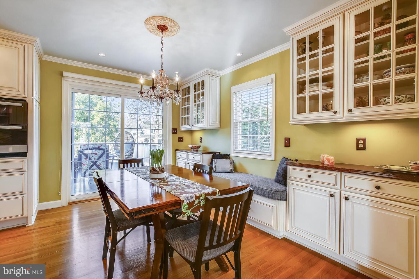 Dining room with white built-in cabinets, a wood table, chandelier, and sliding glass doors to a deck.