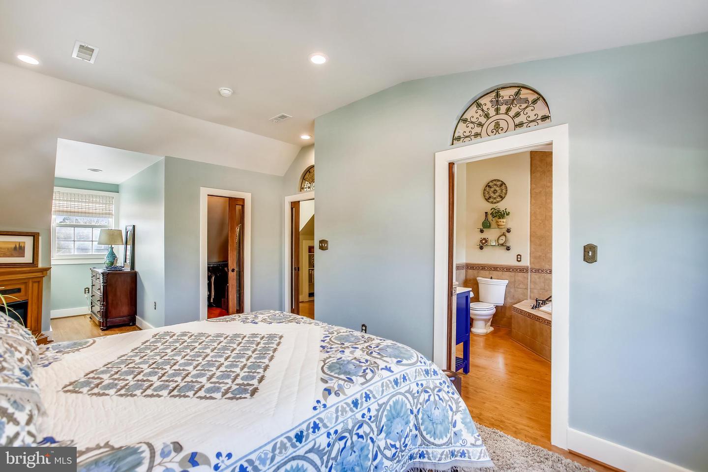 Bedroom with a blue-and-white quilted bed and an open doorway to an adjoining bathroom.