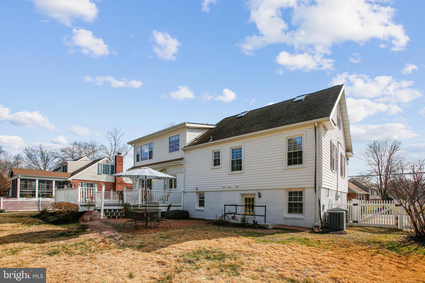 Rear of a white two-story house with a raised deck and brick patio.