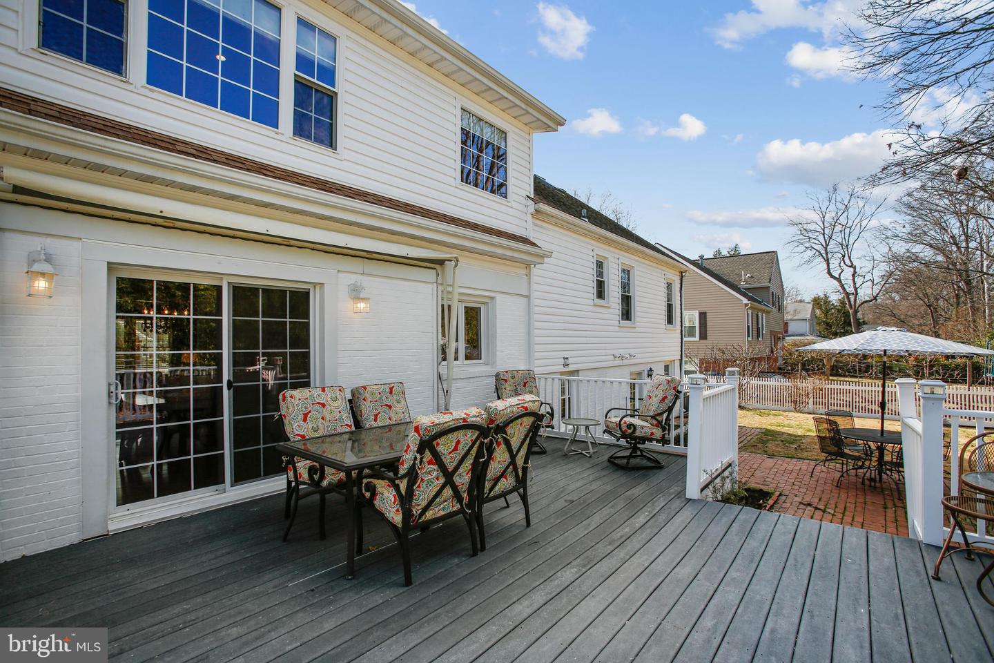 Furnished rear deck with patterned seating, sliding glass doors, and a brick patio beyond.