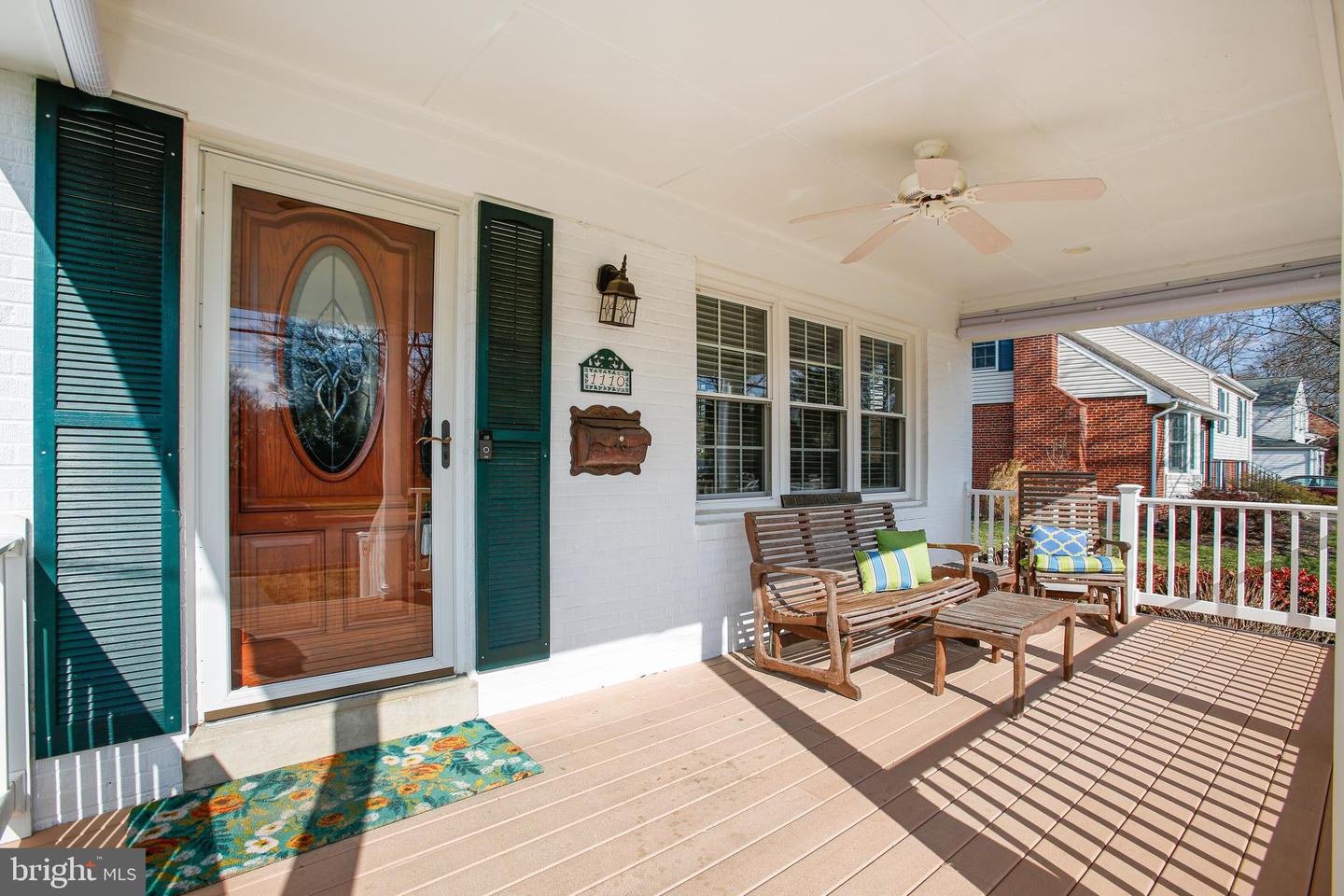 Front porch with a wood door, green shutters, and wooden seating.