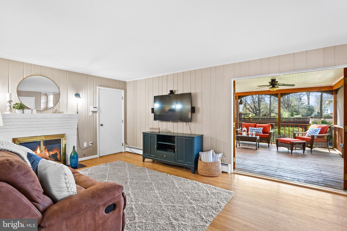 Living room with a white brick fireplace and an open view to a covered deck.