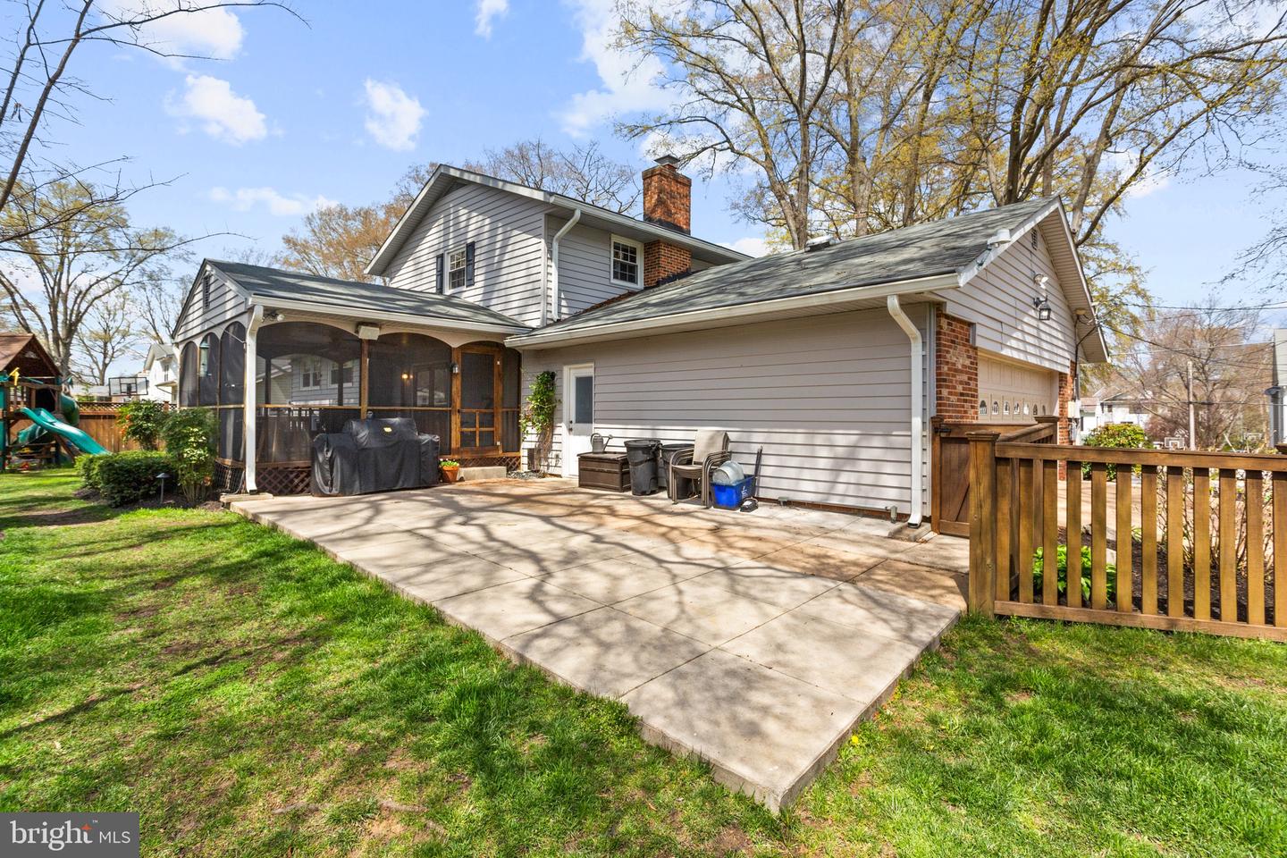 Rear of a two-story house with a broad patio, screened porch, and attached garage.