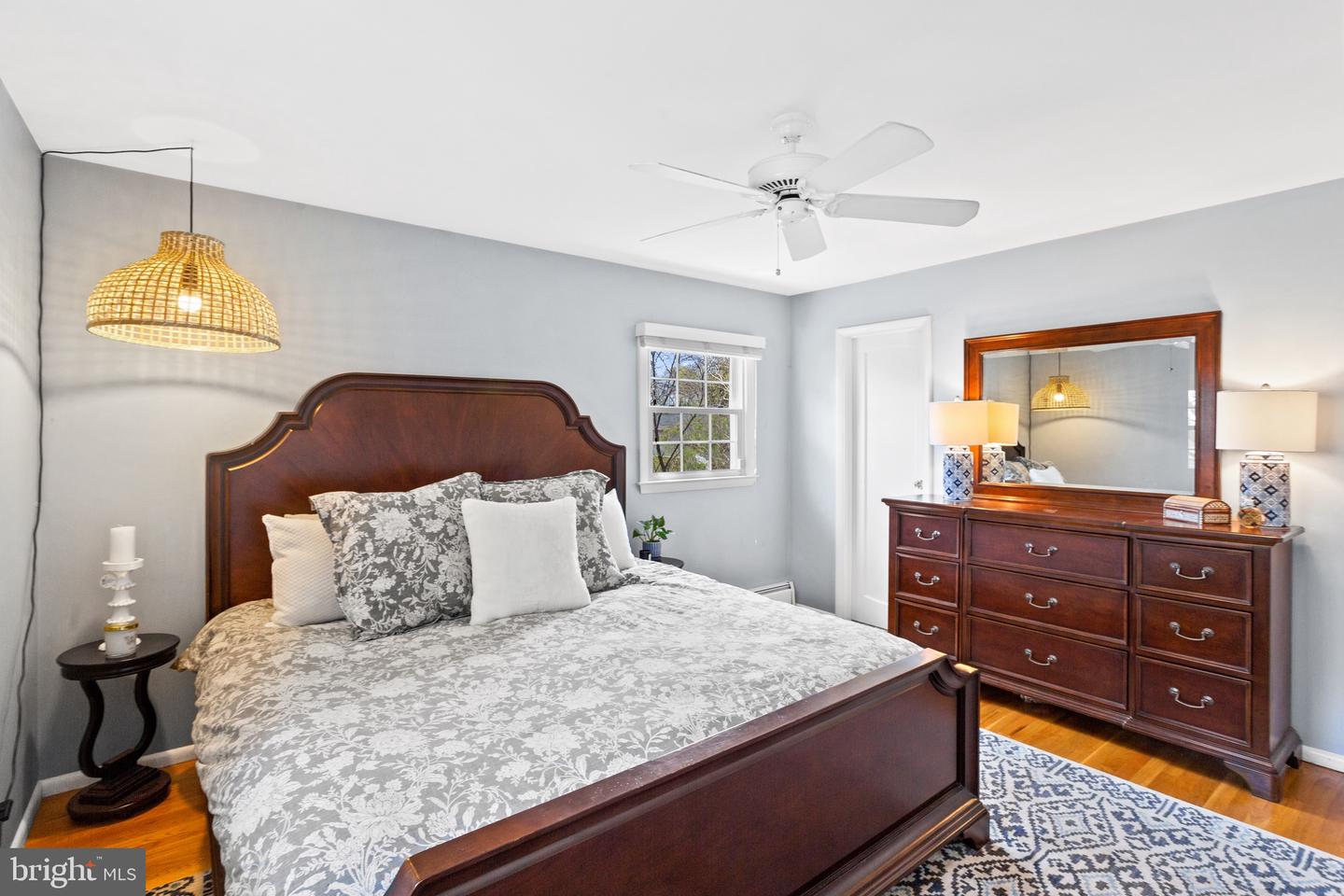 Bedroom with a dark wood bed, gray floral bedding, matching dresser, and patterned rug.