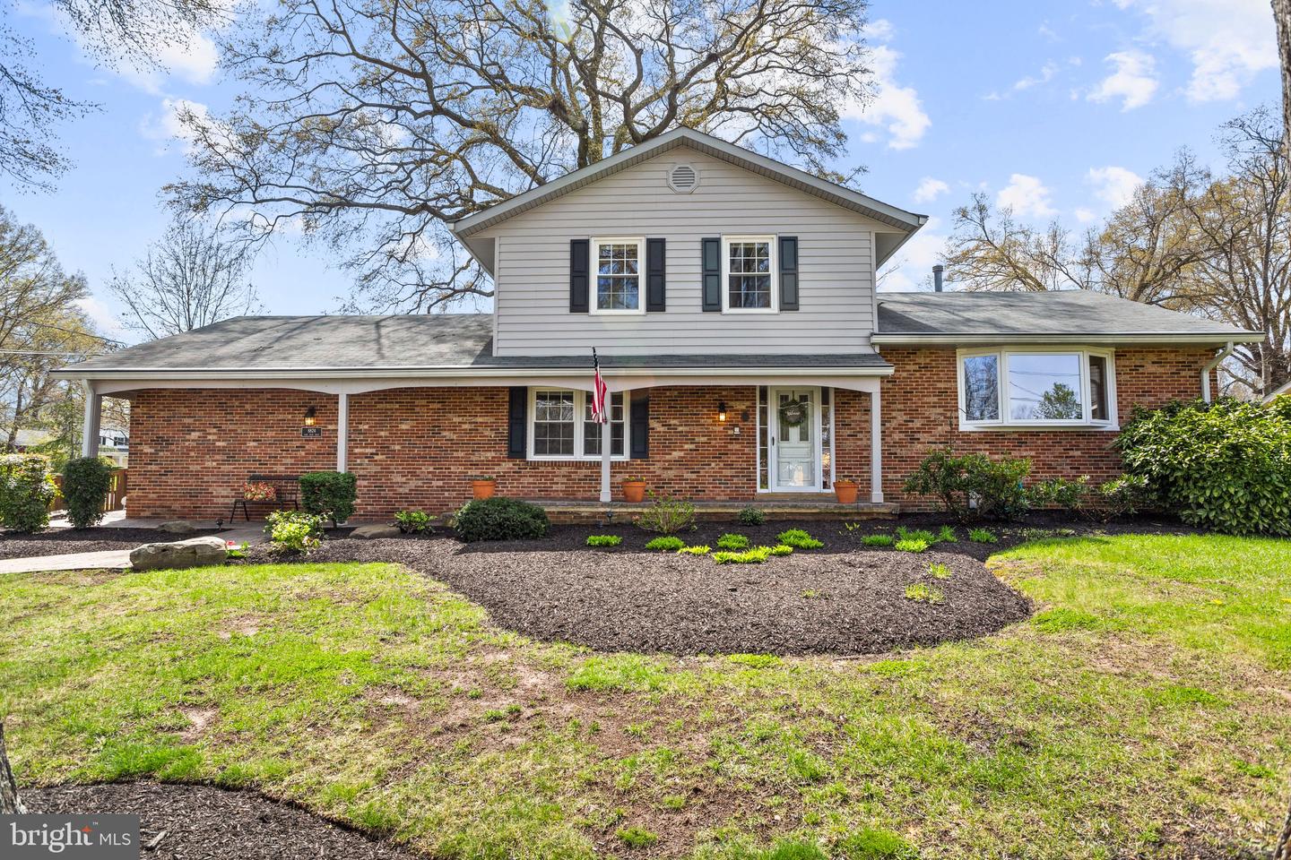 Brick-and-siding home with a covered front porch, bay window, and landscaped yard.
