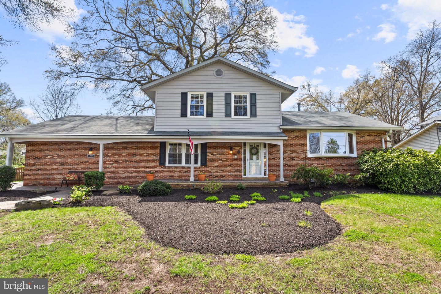 Brick-and-siding home with a covered front porch and landscaped mulch beds.