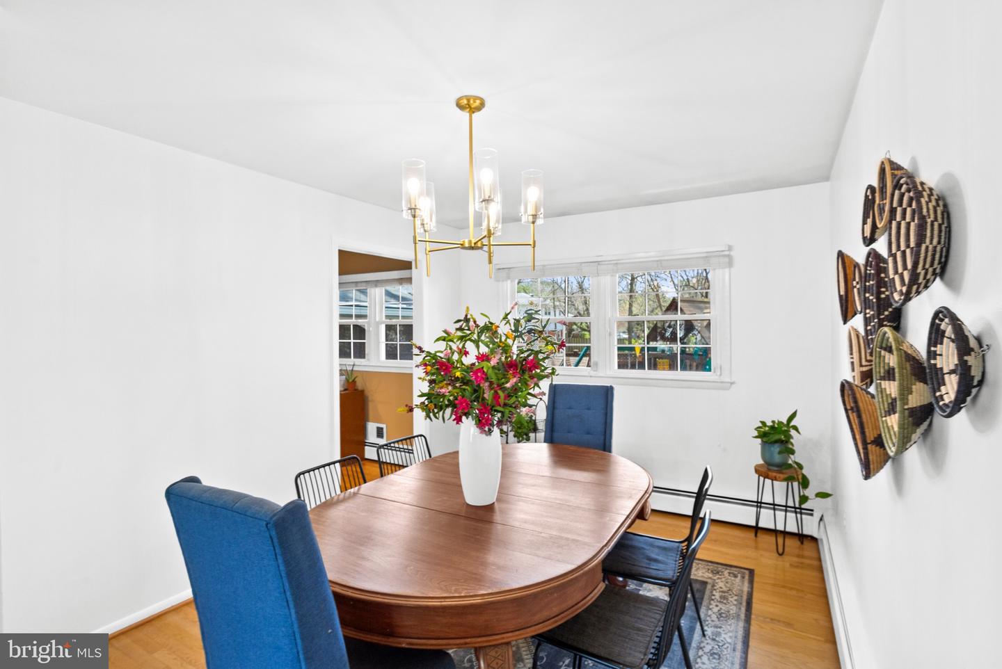 Dining room with an oval wooden table, blue chairs, and a gold chandelier.