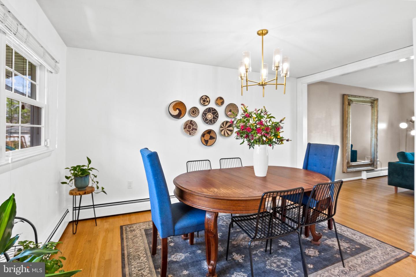 Dining room with an oval wooden table, blue chairs, and a brass chandelier.