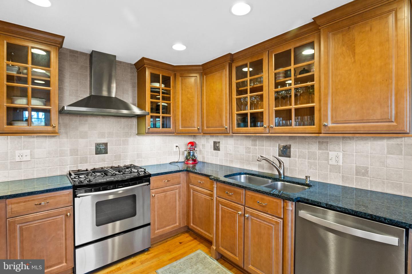 Kitchen with warm wood cabinets, dark countertops, stainless steel appliances, and a gas range.