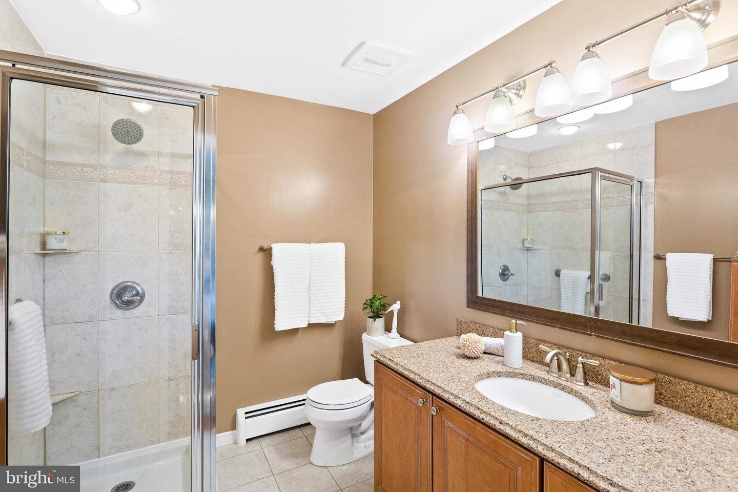 Bathroom with a glass-enclosed tile shower and granite-topped wood vanity.