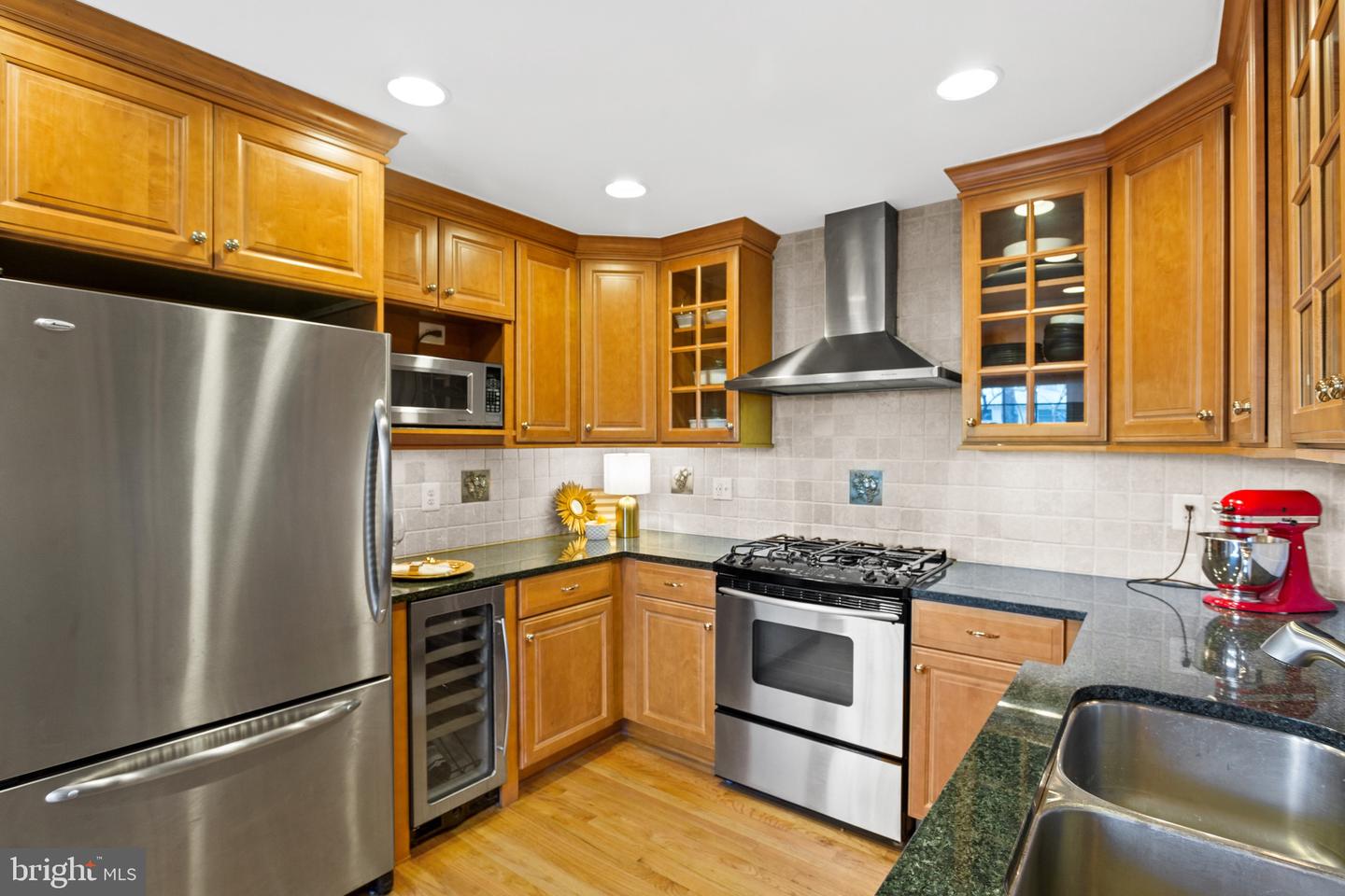 Kitchen with honey-toned cabinets, granite counters, and stainless steel appliances, including a gas range.