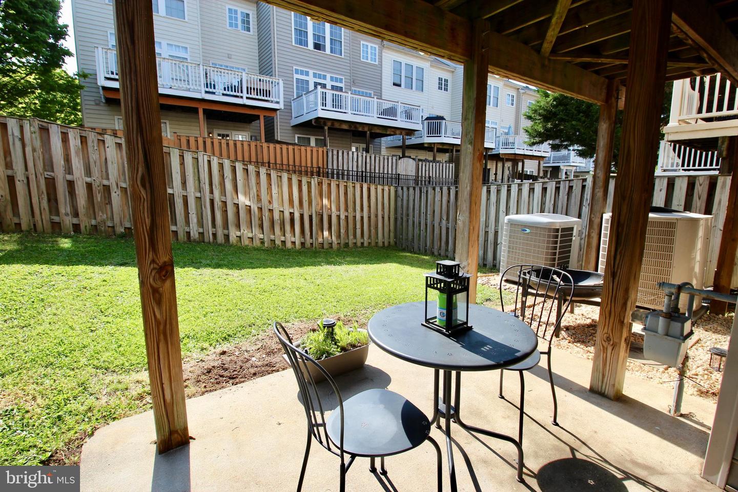 Covered patio with a metal dining set overlooking a fenced lawn.