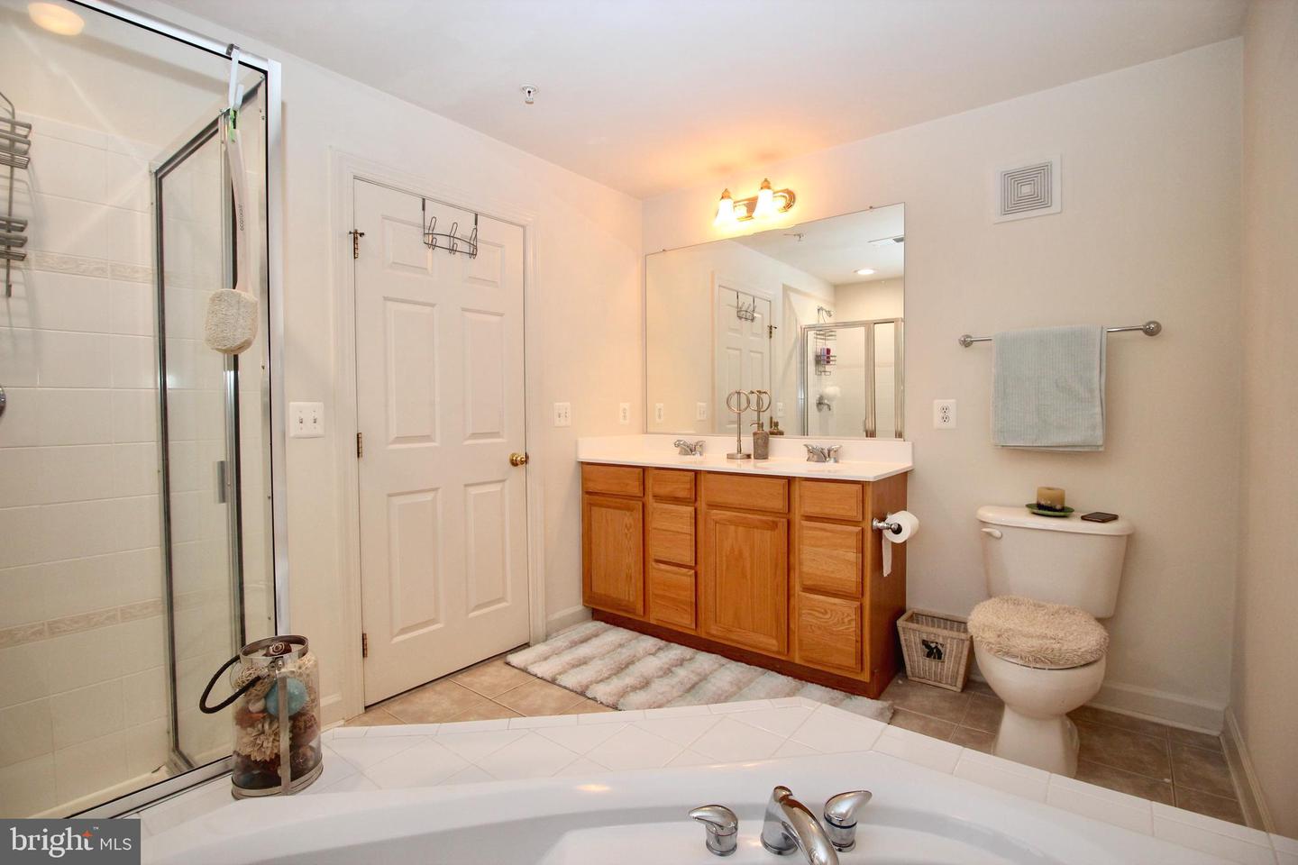 Bathroom with a large bathtub, glass shower, and wood double vanity.