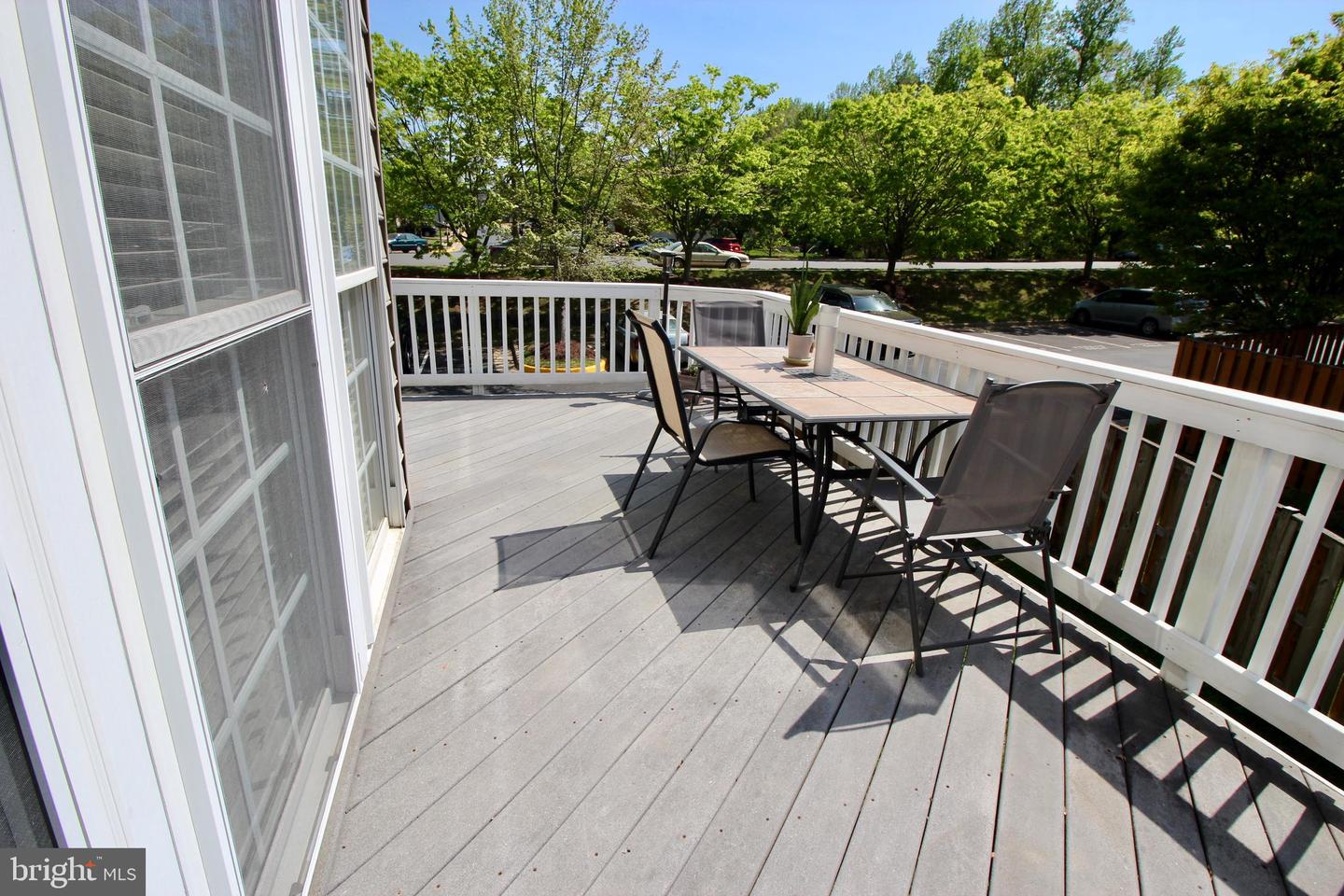 Gray deck with white railings and an outdoor dining table beside sliding glass doors.