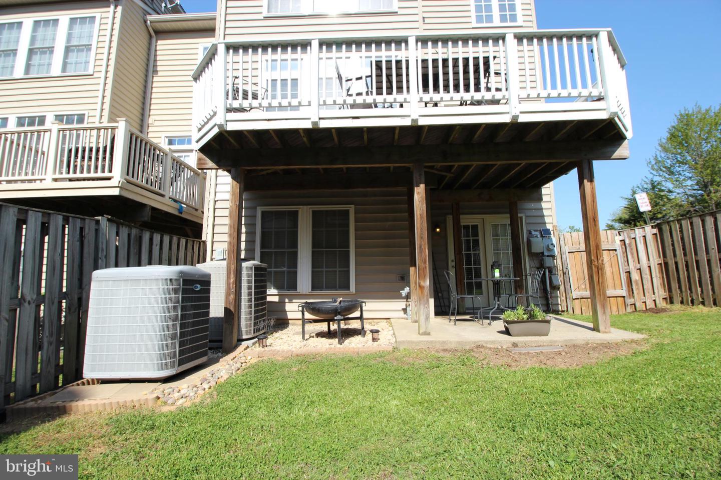Townhouse rear with a raised deck, covered patio, outdoor seating, and fenced lawn.