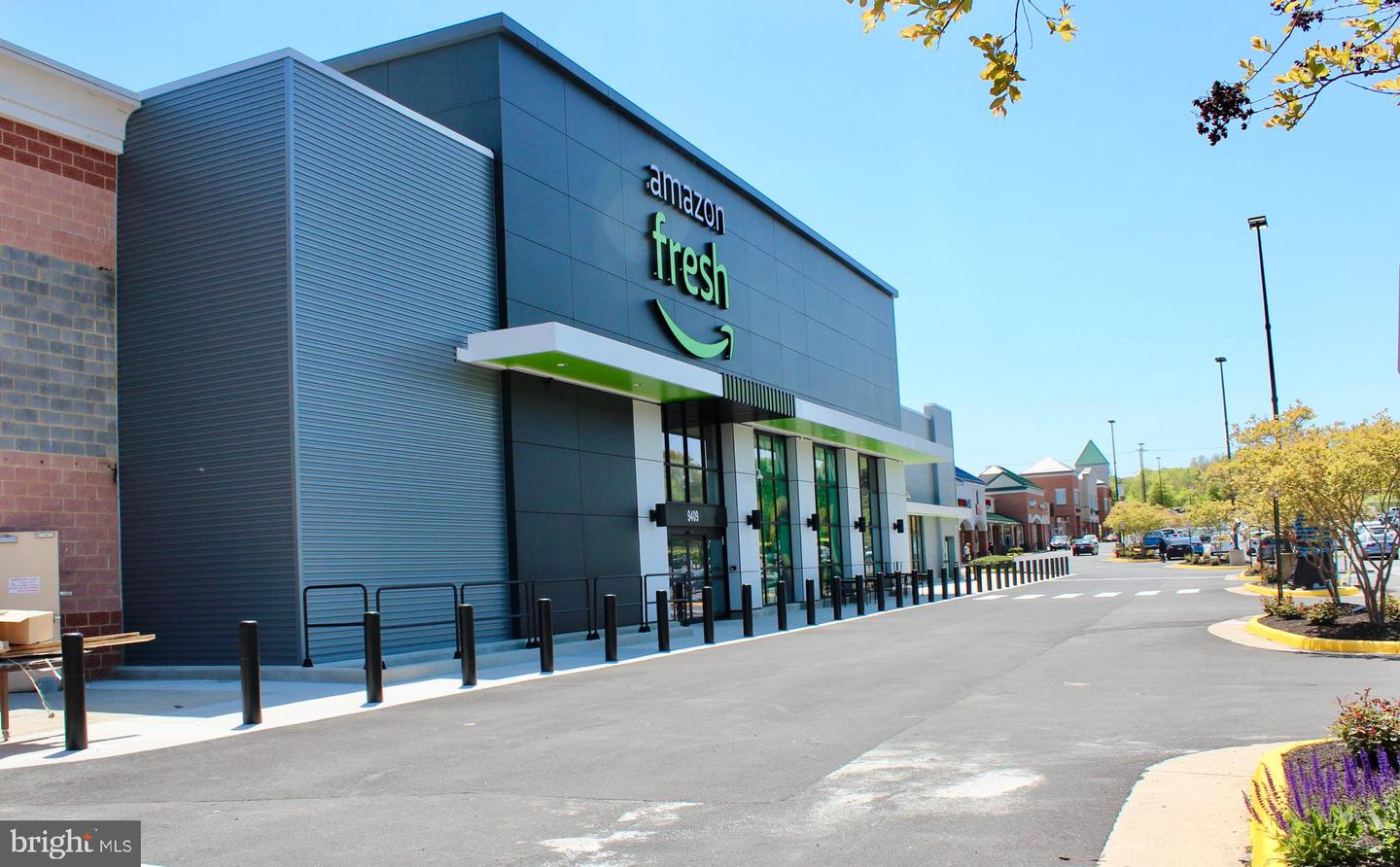 Amazon Fresh storefront in a shopping center, beside a wide access drive and neighboring shops.