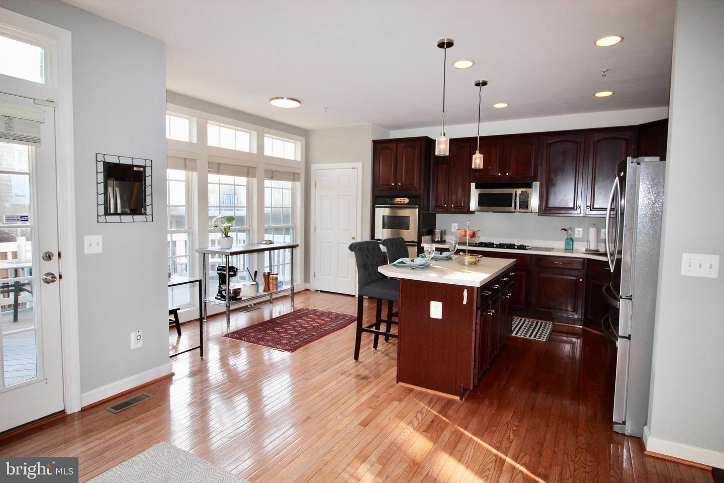 Kitchen with dark cherry cabinets, stainless steel appliances, a large island, and hardwood floors.