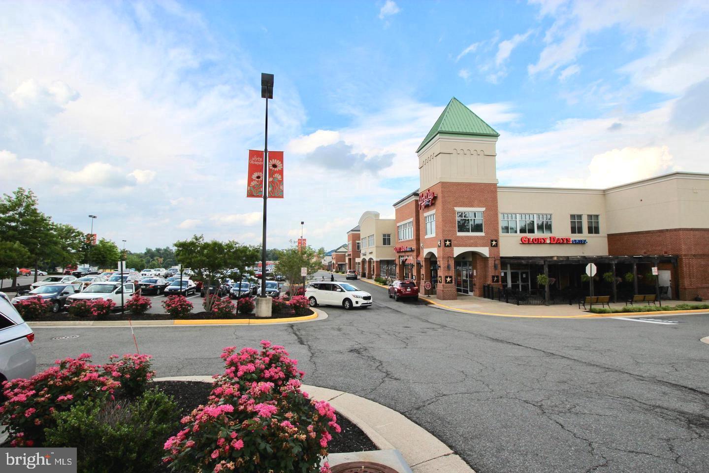 Shopping center with a corner Glory Days Grill storefront, parking lot, and flower beds.