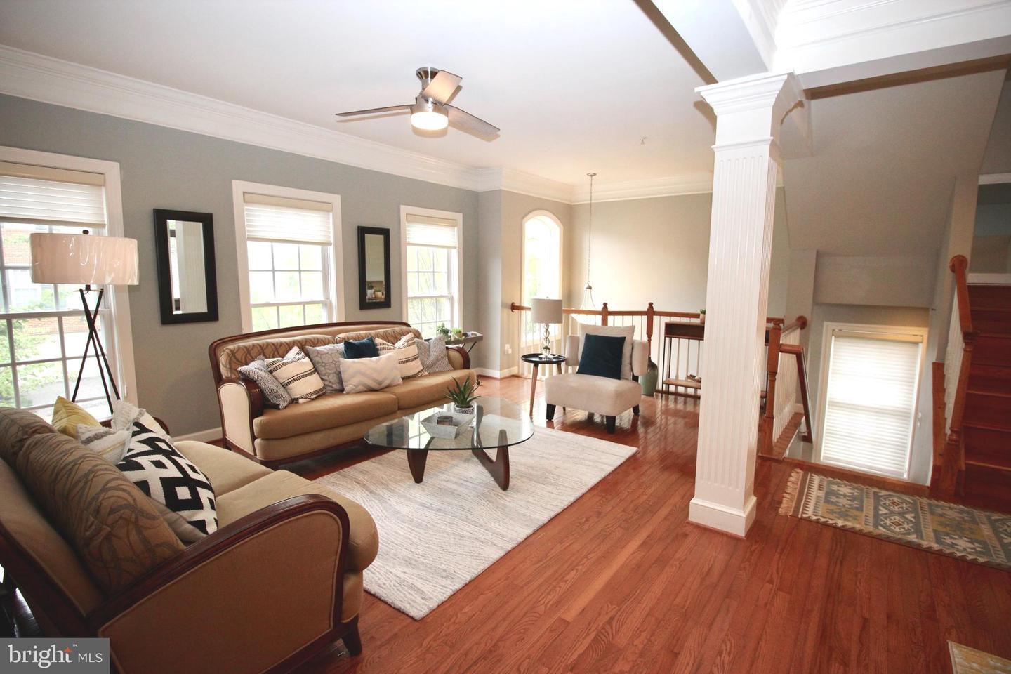Living room with hardwood floors, two sofas, and a glass coffee table beside the staircase.
