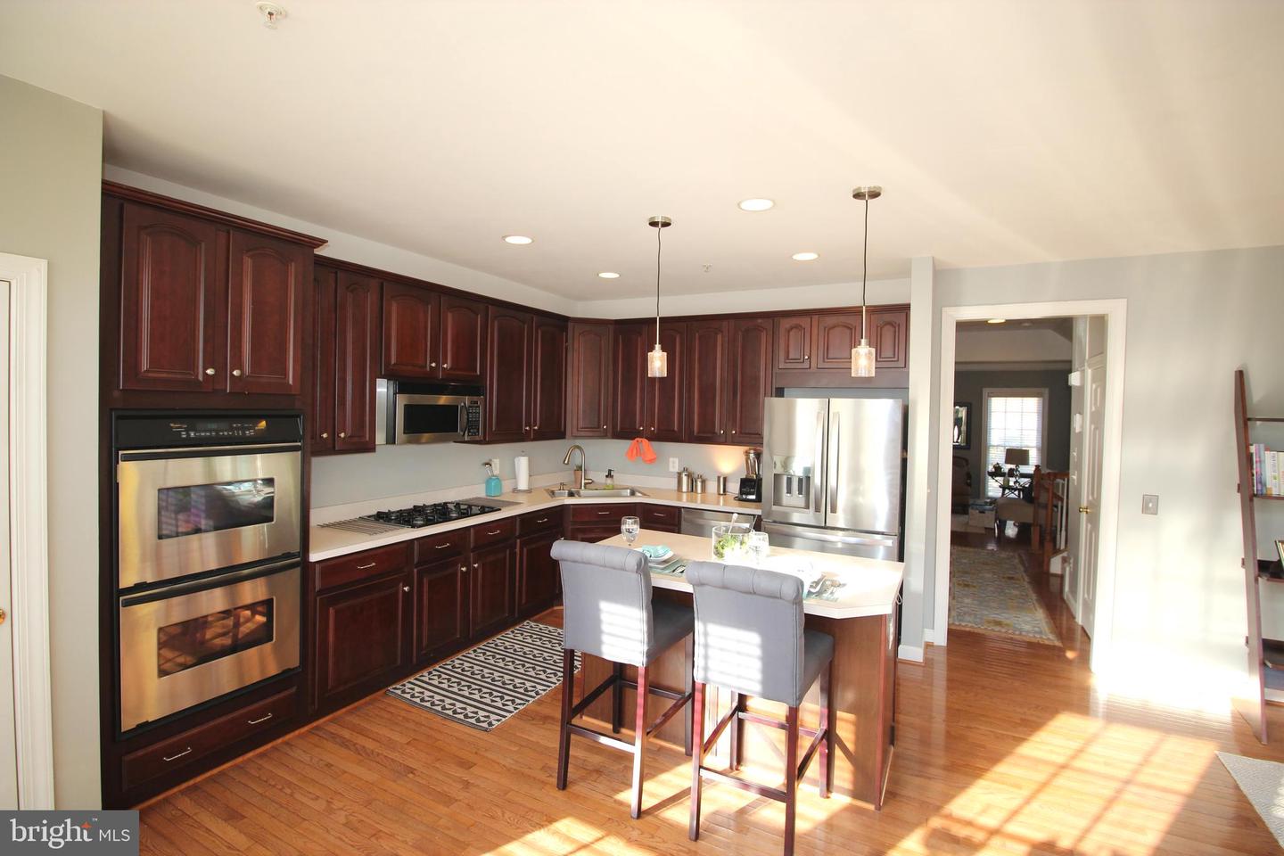 Kitchen with dark cherry cabinets, stainless steel appliances, and a central island with bar stools.