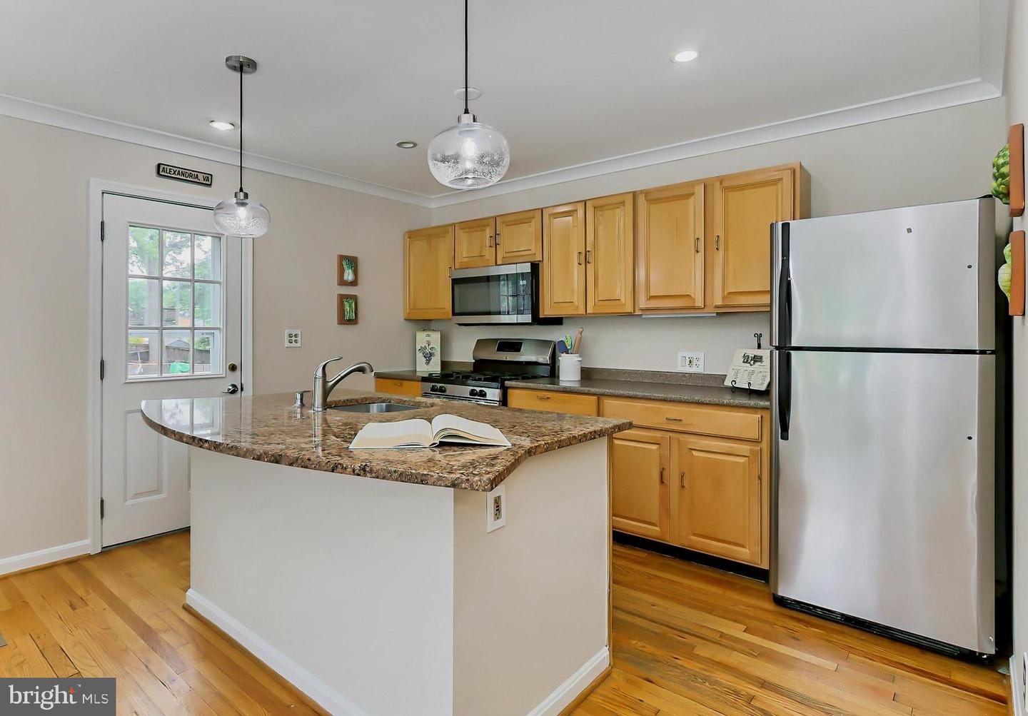 Kitchen with honey-colored cabinets, stainless steel appliances, and a granite-topped island.