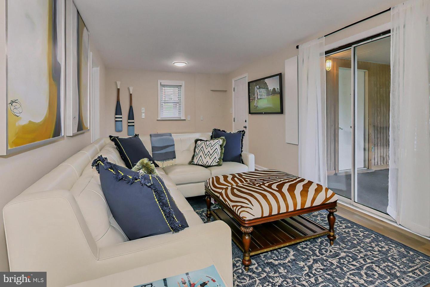 Living room with a white sectional, patterned ottoman, and sliding glass doors to a patio.
