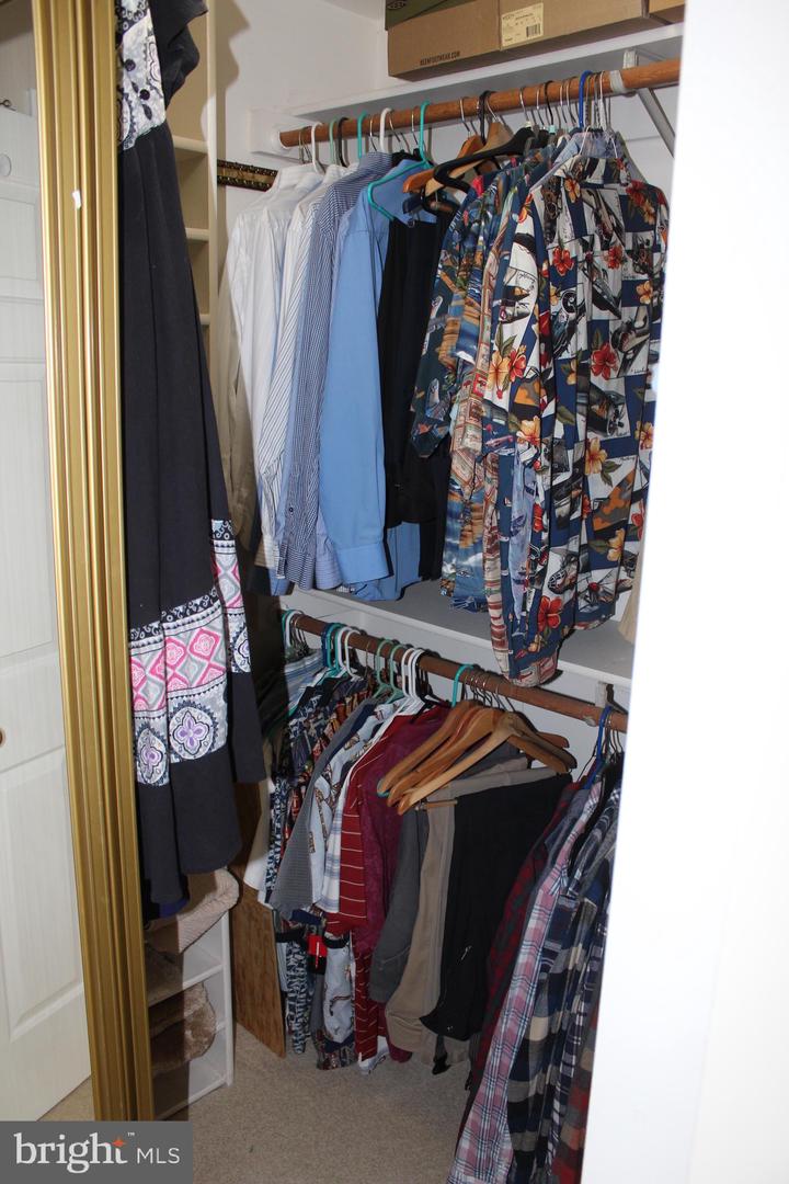 Walk-in closet with two levels of clothing rods and built-in shelving.